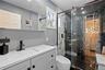 Full bath featuring vanity and a marble finish shower