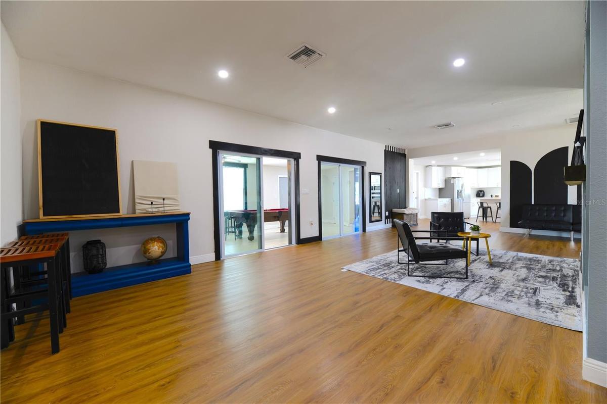 Left to Right:  (2) Step Down into Open Living Area with Wood Slat Wall Accents, Florida Room Entry with 2 sets of Double Sliding Glass Doors into the