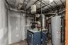 Mechanical room featuring a water heater, boiler system, exposed plumbing lines, and unfinished drywall