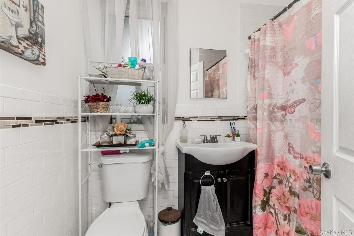 Bathroom featuring white subway tile walls with a decorative mosaic accent band