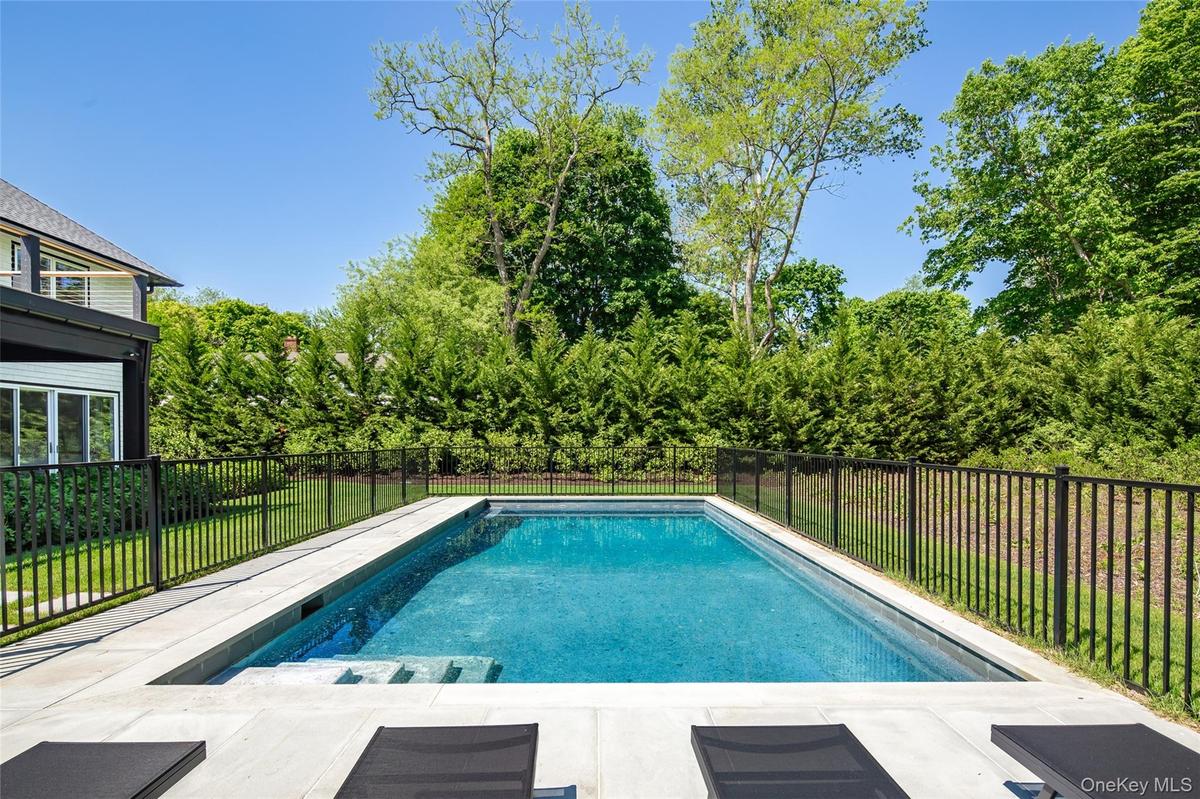 Rectangular inground pool featuring integrated steps and a surrounding patio