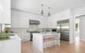 Bright kitchen featuring extensive white cabinetry, a central island with countertop seating, stainless steel appliances, light wood-finish flooring, 