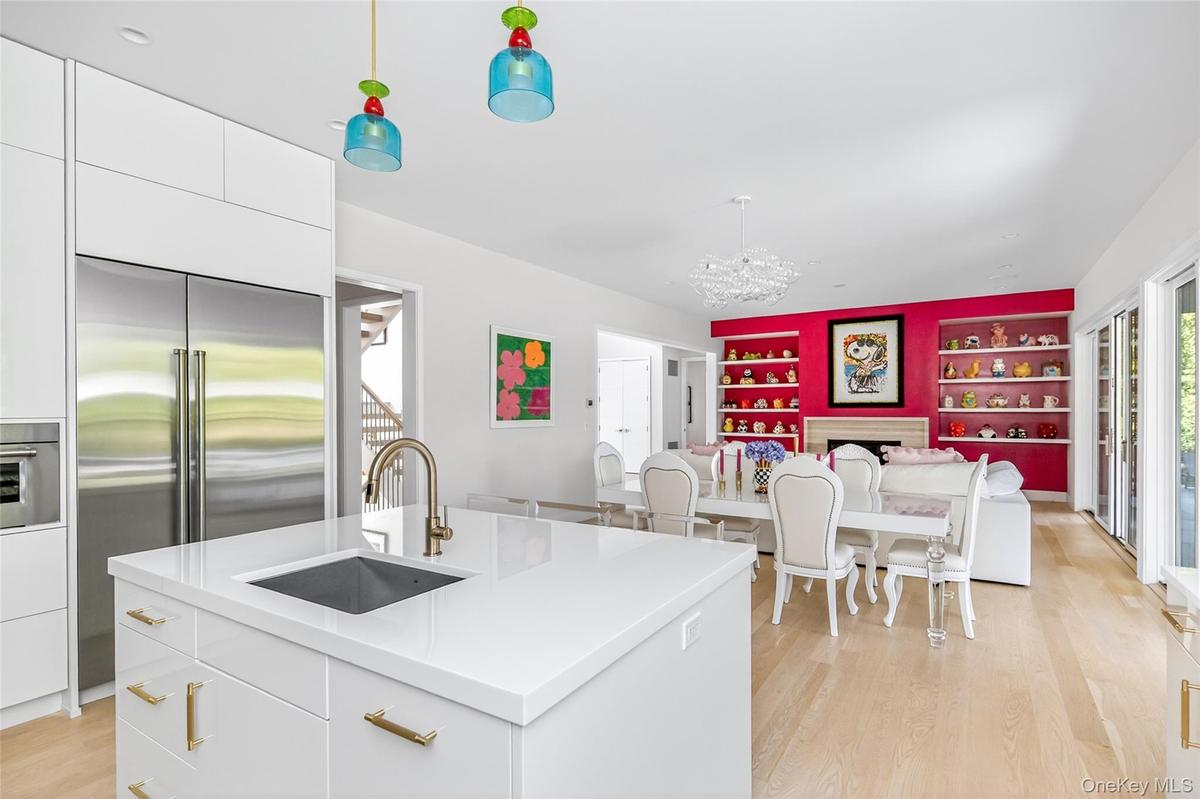Kitchen island with integrated sink and brass-finish faucet, featuring white cabinetry and light wood-finish flooring
