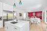 Kitchen island with integrated sink and brass-finish faucet, featuring white cabinetry and light wood-finish flooring