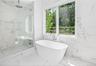 Bathroom featuring a freestanding soaking tub with floor-mounted faucet, a walk-in shower with a built-in bench and rainfall showerhead, and expansive