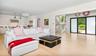 Open-concept living space with light wood-finish flooring, a contemporary kitchen featuring white cabinetry and stainless steel appliances, a modern s