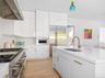 Contemporary kitchen featuring white flat-panel cabinetry, a stainless steel range with matching hood, and built-in microwave
