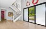 Grand entry featuring a light wood-finish flooring, a contemporary staircase with wood handrails and white risers, and tall ceilings