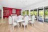 Spacious room featuring light wood-finish flooring, a contemporary chandelier, and a prominent red accent wall with built-in shelving flanking a firep