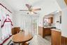 Dining area featuring wood-finish flooring, half-wall wainscoting, and a ceiling fan with integrated lighting