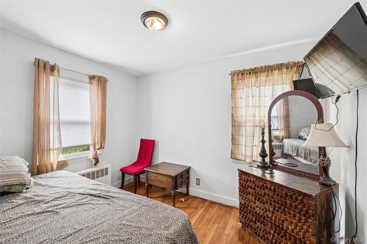 Bright interior space featuring a window with blinds, wood-finish flooring, and a ceiling-mounted light fixture
