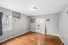 Hardwood flooring and light gray walls define this room, featuring a window-mounted air conditioning unit and baseboard heating