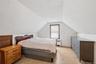 Attic space featuring sloped ceilings, white wall finishes, and a single window with wood trim