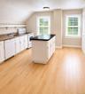 The second-floor kitchen features beautiful white cabinetry and a spacious center island, creating a bright and inviting space perfect for cooking, ga