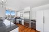 Gourmet kitchen featuring a large island with a dark stone countertop, stainless steel appliances, white cabinetry, and wood-finish flooring