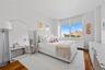 Room featuring wood-finish flooring, white walls, and a large window with roller shades
