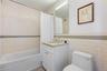 Bathroom featuring a white subway tile surround with a glass mosaic accent band, a white vanity with a light-toned countertop, a rectangular mirror wi