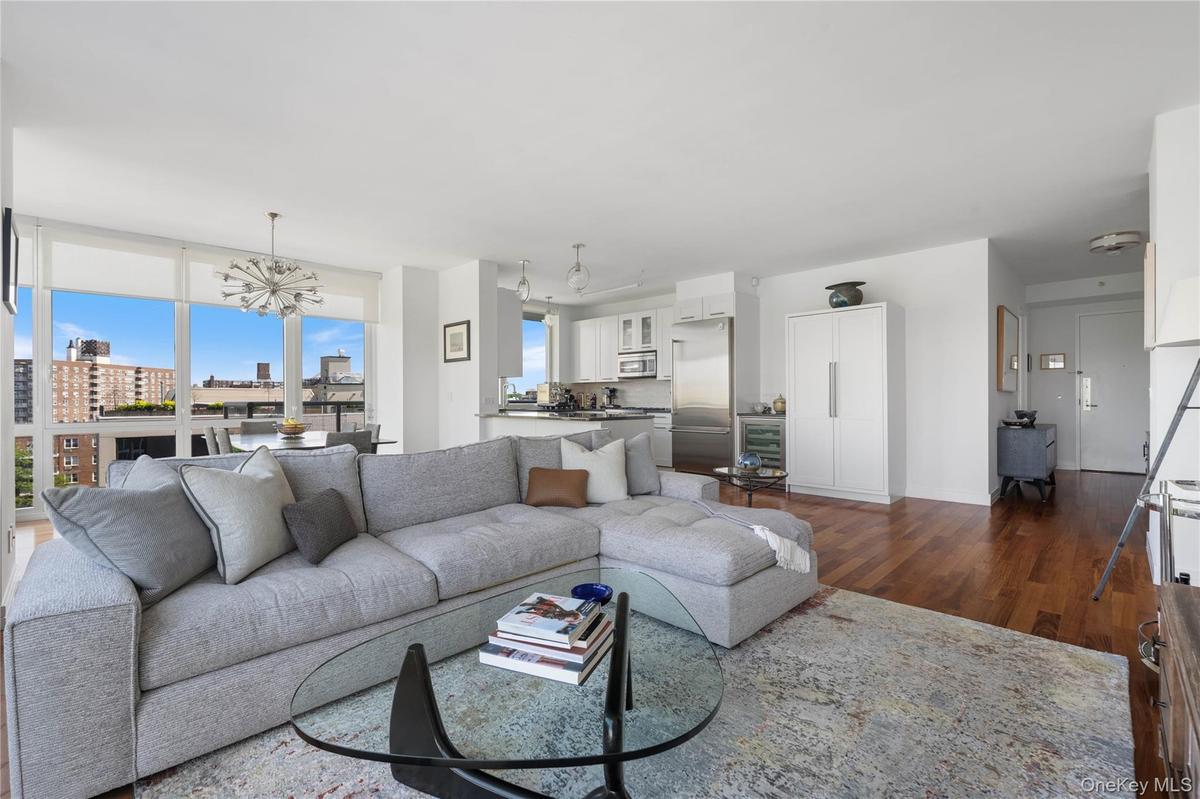 Open-concept living space featuring wood-finish flooring, a contemporary kitchen with stainless steel appliances, and a dining area with a modern sput