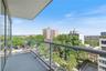 Private balcony featuring a clear glass railing and an expansive urban landscape