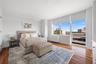 Bright room with extensive window system featuring roller shades, wood-finish flooring, and white walls