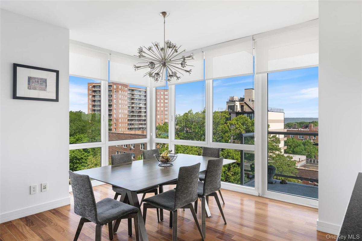 Dining area featuring expansive floor-to-ceiling windows, wood-finish flooring, and a modern sputnik chandelier