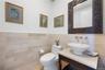 Powder room featuring a vessel sink, wall-mounted faucet, and a decorative carved mirror