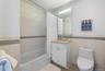 Bathroom featuring a white subway tile surround with a glass mosaic accent band, a white vanity with a light-toned countertop, a rectangular mirror wi