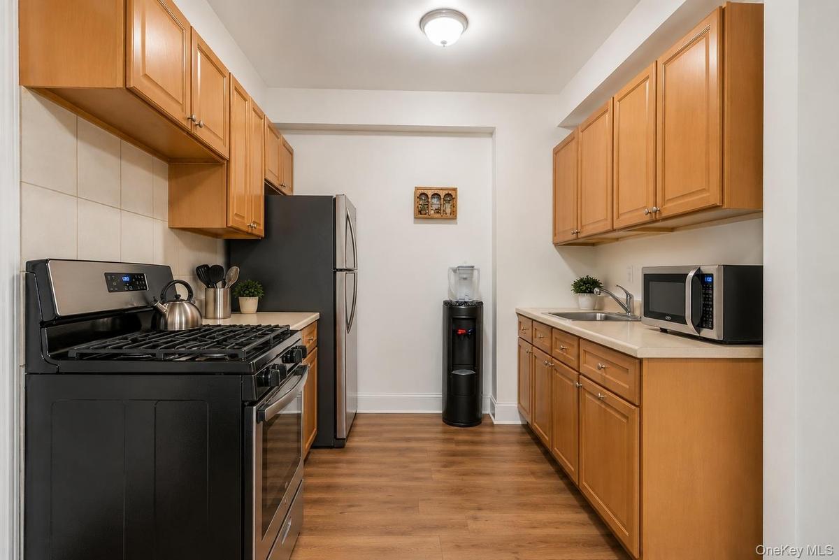 Galley kitchen featuring wood-finish cabinetry, light countertops, and a full-size range with a stainless steel and black finish