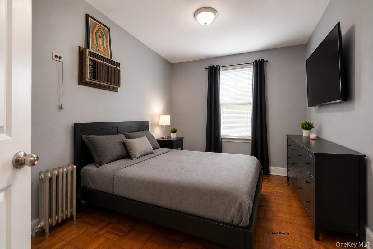 Room featuring wood-finish parquet flooring, a window with blinds, and light gray walls