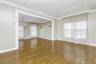 Unfurnished room with a chandelier, plenty of natural light, wood finished floors, baseboards, and ornamental molding