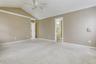 Unfurnished room with a ceiling fan, lofted ceiling, baseboards, crown molding, and light carpet