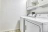 Laundry room with washing machine and dryer, cabinet space, light tile patterned flooring, and baseboards