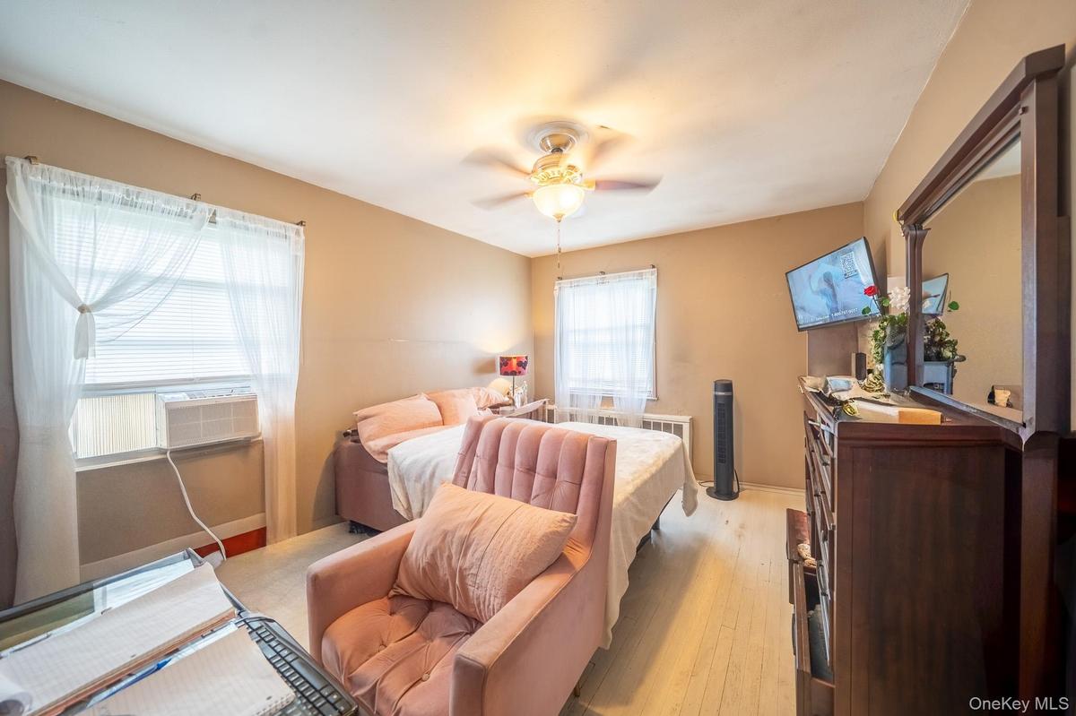 Bedroom with light wood-style floors, a ceiling fan, and cooling unit