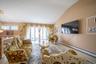 Living room with vaulted ceiling, healthy amount of natural light, baseboard heating, and wood finished floors