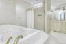 Full bathroom featuring a tub with jets, crown molding, tile patterned floors, vanity, and tile walls