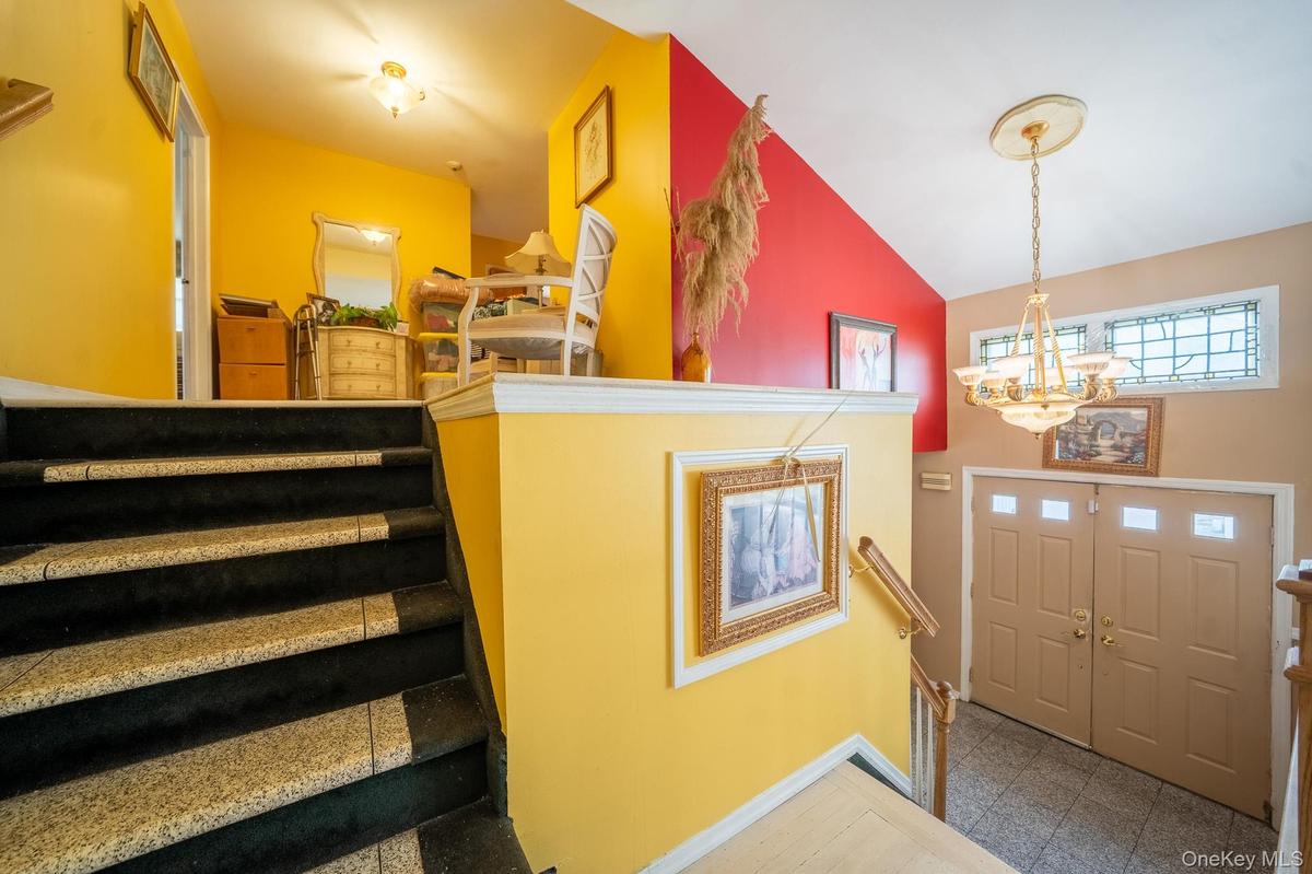 Foyer entrance with a chandelier, vaulted ceiling, stairs, and granite tiled floors