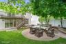 Expansive backyard featuring a circular paver patio, stone-faced raised planters, and a manicured lawn