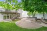 Expansive backyard featuring a circular paver patio, a built-in stone block counter, and a stone retaining wall