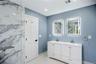 Modern en-suite bathroom featuring a double vanity with white cabinetry and integrated sinks, illuminated by two LED mirrors