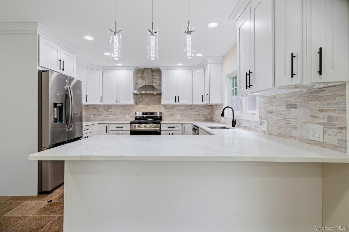 White kitchen featuring a U-shaped layout, quartz countertops, and a full tile backsplash