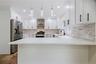 White kitchen featuring a U-shaped layout, quartz countertops, and a full tile backsplash