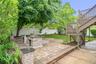 Paved patio area featuring two stone-clad built-in structures, a tiered wooden deck with railings and staircase, and a manicured lawn
