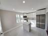 Kitchen featuring a center island, white cabinets, tasteful backsplash, light stone counters, and stainless steel appliances