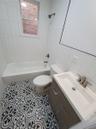 Full bathroom with tile patterned floors, vanity, tile walls, toilet, and tiled shower / bath