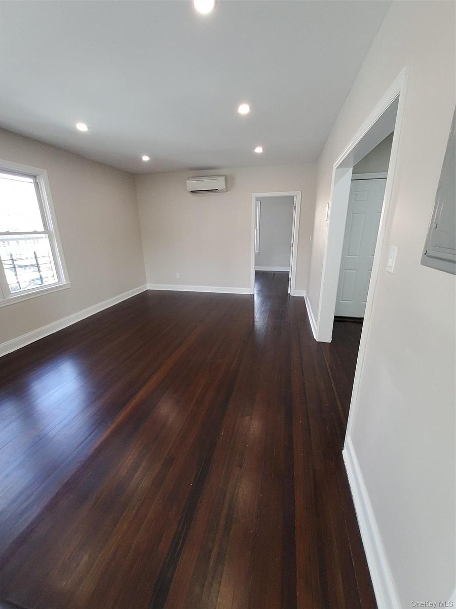 Unfurnished room with a wall mounted AC and dark hardwood / wood-style floors
