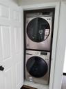 Clothes washing area with stacked washer / drying machine and dark hardwood / wood-style floors