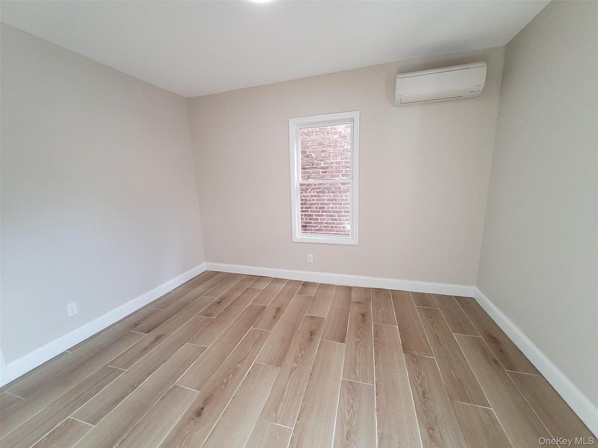 Unfurnished room featuring an AC wall unit and light hardwood / wood-style floors