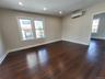 Unfurnished room with an AC wall unit, plenty of natural light, and dark wood-type flooring