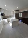 Kitchen featuring light stone countertops, refrigerator, sink, white cabinets, and a kitchen island