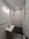 Bathroom featuring a tile shower, tile patterned floors, vanity, and tile walls